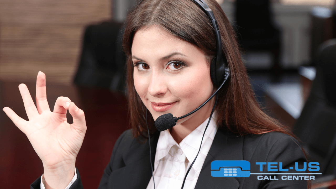 A smiling call center agent wearing a headset and giving an OK sign.