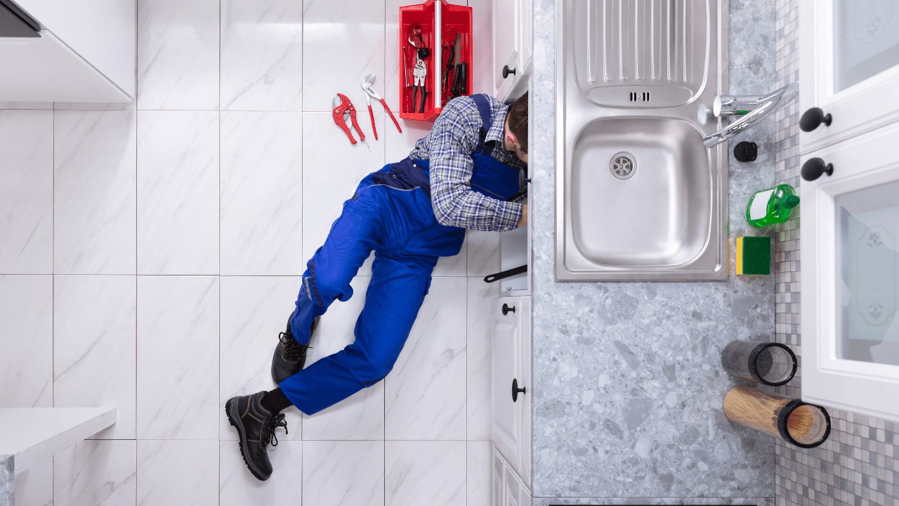 Top-down view of a person lying on a white-tiled kitchen floor near a doorway.