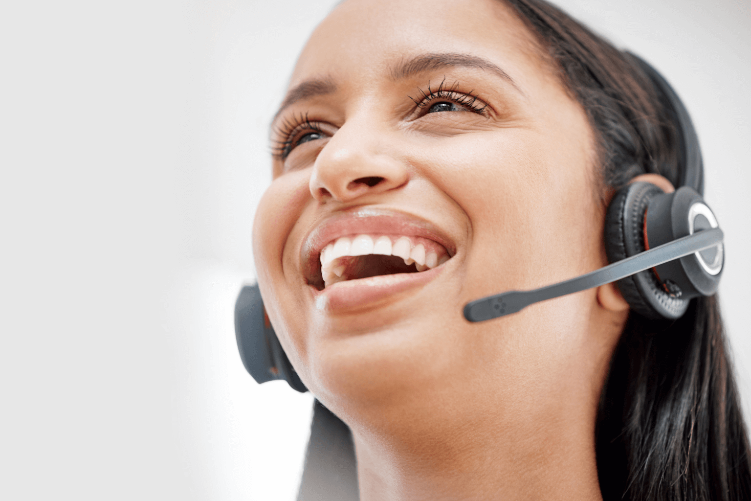A smiling woman wearing a headset with a microphone.